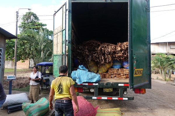 A large truck's trailer is open, revealing baskets of dried leaves