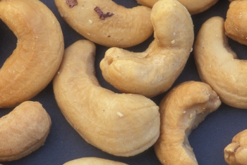 Shelled cashew nuts, some with small bits of brown, papery skin still clinging, in a pile